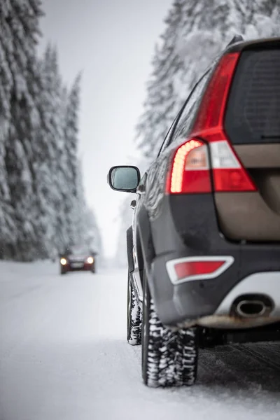 Coche en un camino nevado de invierno en medio de bosques — Foto de Stock