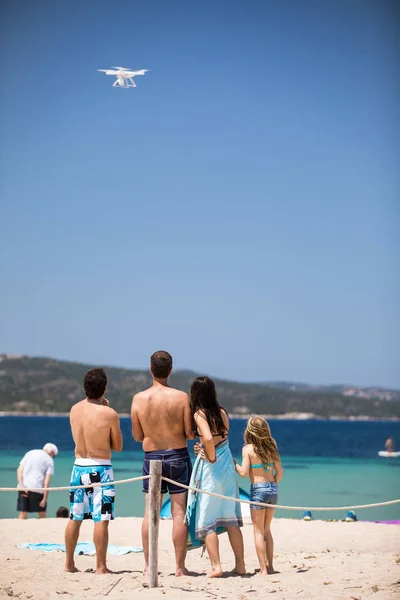 Unga människor flyga en drönare med fjärrkontroll på en strand — Stockfoto