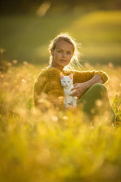 Bonita, jovem mulher com seu animal de estimação gato sentado na grama — Fotografia de Stock