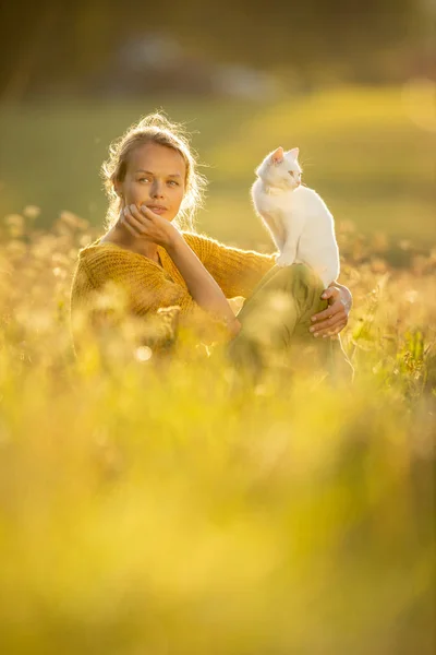 Krásná mladá žena s kočičí mazlíčkem sedící v trávě — Stock fotografie