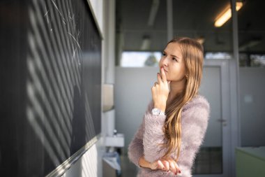 Bir tahta önünde güzel, genç kız öğrenci 