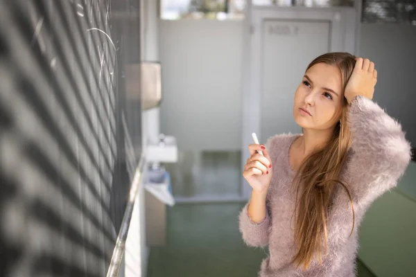 Pretty, young female student in front of a blackboard — Stock Photo, Image