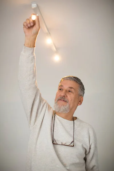 Homem sênior instalando uma luz de teto — Fotografia de Stock