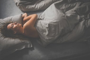 Güzel, orta yaşlı bir kadın evinde yatağında uyuyor.