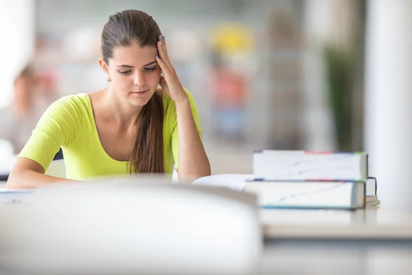 Bonito estudante universitário / colegial feminino com livros na biblioteca — Fotografia de Stock