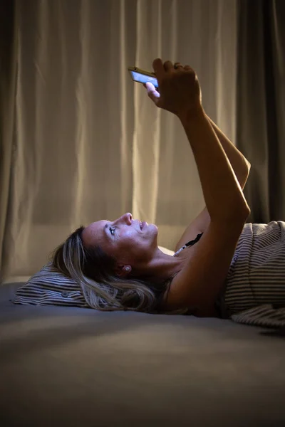 Csinos, középkorú nő használja a táblagépét alvás előtt. — Stock Fotó