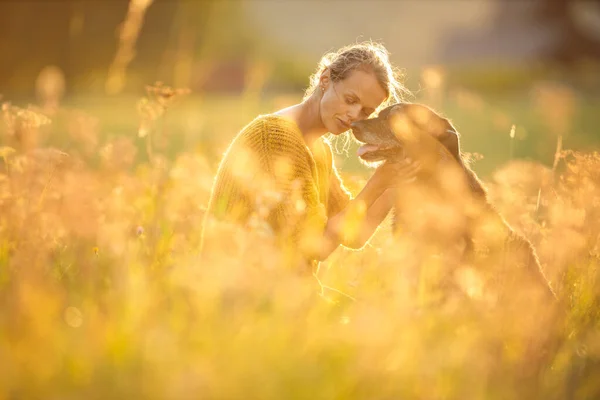 Söt, ung kvinna med sin stora svarta hund — Stockfoto