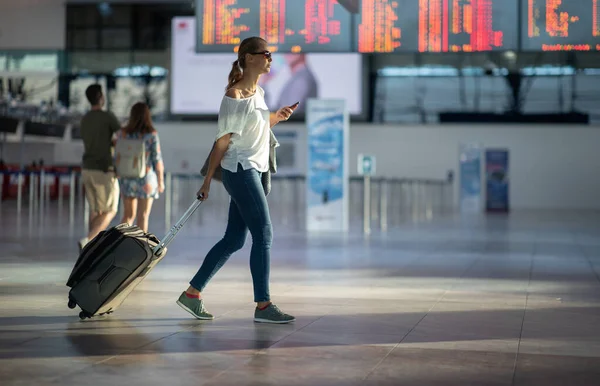 Молодая женщина со своим багажом в международном аэропорту, прежде чем — стоковое фото
