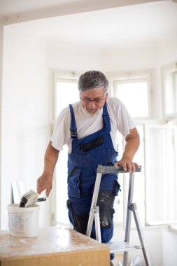 Son sınıf öğrencisi beyaz bir oda boyuyor, duvar boyama konsepti.
