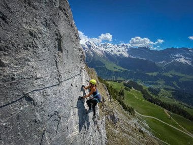 İsviçre Alplerinde dik bir Via Ferrata 'da korkusuzca tırmanan güzel bir kadın dağcı.