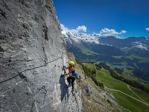 スイスアルプスのフェラタ経由で急斜面を登るかなりの女性登山家 この極端な高山歩道で恐ろしいほど高く登る — ストック写真