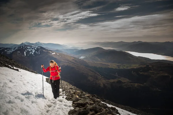 年轻的女徒步旅行者爬山时 身边环绕着灿烂的小山 — 图库照片