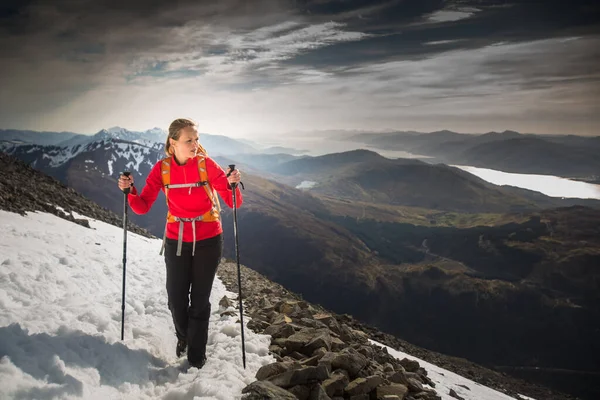 年轻的女徒步旅行者爬山时 身边环绕着灿烂的小山 — 图库照片