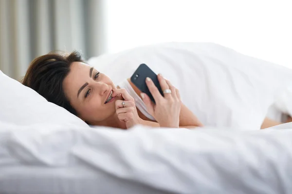 아름다운 여성이 아침에 일어나자마자 스마트폰으로 있습니다 — 스톡 사진