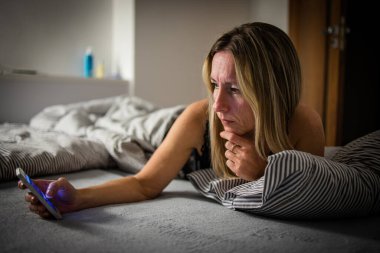 Güzel, orta yaşlı bir kadın akşamları yatmadan önce tabletini kullanıyor.