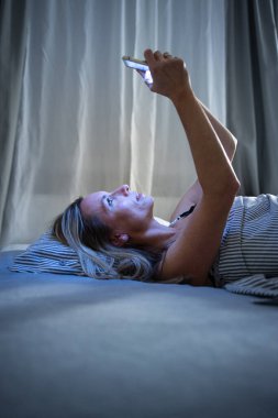 Güzel, orta yaşlı bir kadın uyumadan önce evde tablet bilgisayar kullanıyor. Bluelight 'a maruz kalıyor.