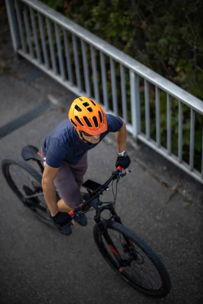 Cross country mtb biker going for his favorite hills beyond the city limits (top view; shallow DOF)