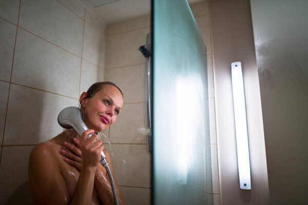 Молодая женщина моет волосы шампунем, принимает горячий долгий душ