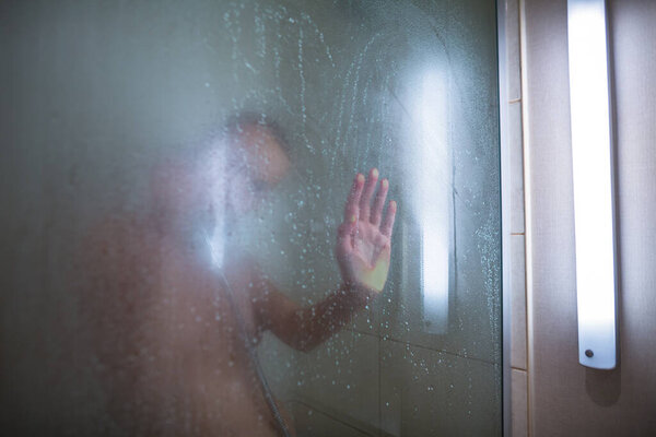Молодая женщина моет волосы шампунем, принимает горячий долгий душ