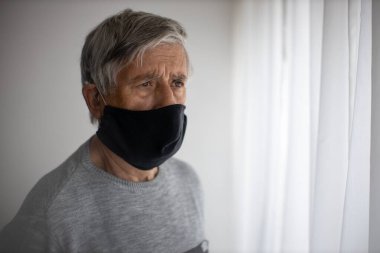 Koronavirüs ve grip salgını sırasında maske takan kıdemli bir adam. Virüs ve hastalık koruması, ev karantinası. COVID-19 kavramı