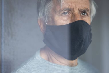 Koronavirüs ve grip salgını sırasında maske takan kıdemli bir adam. Virüs ve hastalık koruması, ev karantinası. COVID-19 kavramı
