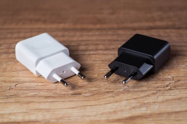 Ahşap masa üzerinde siyah beyaz cep telefonu şarj cihazları