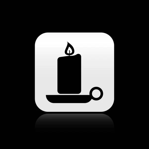 Black Burning candle in candlestick icon isolated on black background. Old fashioned lit candle. Cylindrical candle stick with burning flame. Silver square button. Vector Illustration — Stock Vector