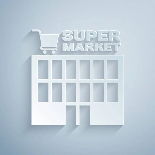 Papier gesneden supermarkt gebouw met winkelwagentje icoon geïsoleerd op grijze achtergrond. Winkel of winkel. Mall Building. Papier kunststijl. Vector illustratie — Stockvector