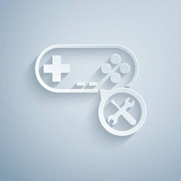 Papier knippen gamepad met schroevendraaier en moersleutel pictogram geïsoleerd op grijze achtergrond. Aanpassing, service, instelling, onderhoud, reparatie, bevestiging. Papier kunststijl. Vector illustratie — Stockvector