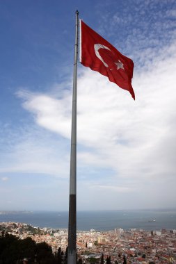 Mavi gökyüzüne ve İzmir panoramasına karşı Türk bayrağı.