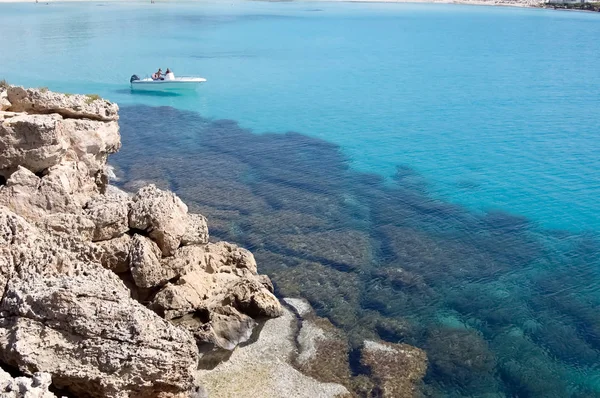 Barca bianca e mare blu trasparente vicino alla riva rocciosa di Cypr — Foto Stock