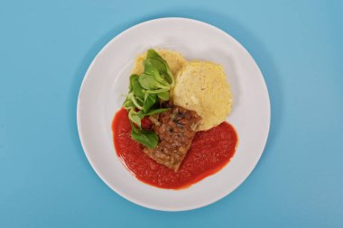 Tempeh domates sosu ve mavi bir arka plan üzerinde köfte ile