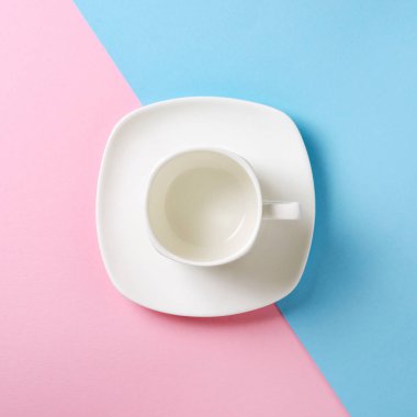 Boş beyaz Kupası ve fincan tabağı pembe ve mavi arka plan üzerinde. Düz yatıyordu kavramı. Pastel tonları