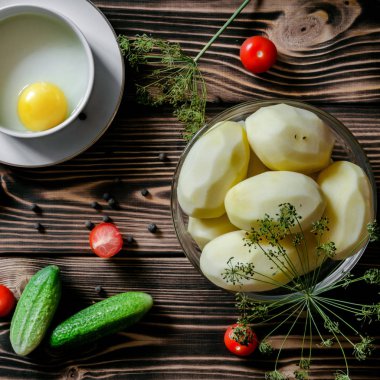 Tavuk yumurta, ham patates, taze salatalık ve? herry domates dereotu dalları ahşap bir zemin üzerine. Gıda kavramı