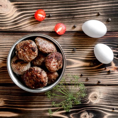 Bir kase, iki yumurta ve domates dereotu branche ve yenibahar ahşap bir zemin üzerine kızarmış et köftesi. Gıda kavramı