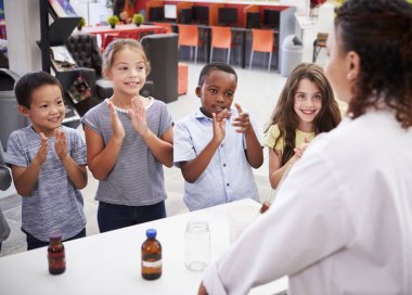 Classmates applauding teacher after science experiment clipart