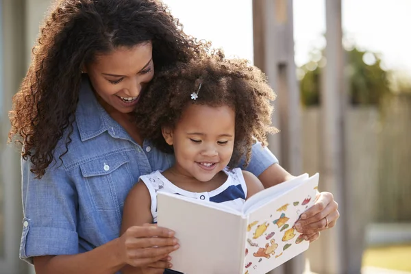 Ung Flicka Läsa Bok Sitter Mammas Knän Utomhus — Stockfoto