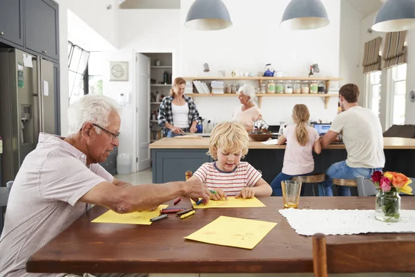 爷爷和孙子一起在忙碌的家庭厨房里画画 — 图库照片