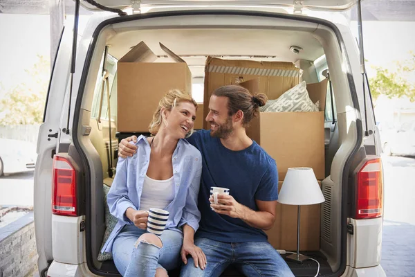 Couple Taking Break In Back Of Removal Truck On Moving Day