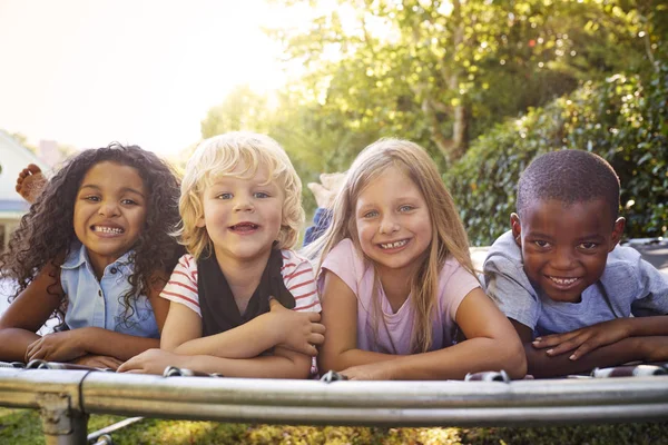 Cuatro Niños Acostados Juntos Trampolín Jardín — Foto de Stock