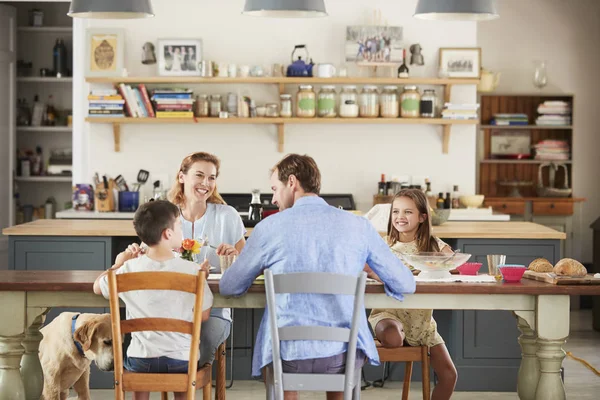 Family with dog eating together at table in kitchen