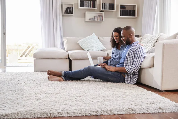 年轻夫妇使用笔记本电脑坐在地板上在家 — 图库照片