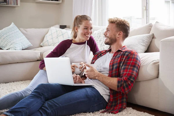 年轻夫妇坐在地板上 在家里使用笔记本电脑 — 图库照片
