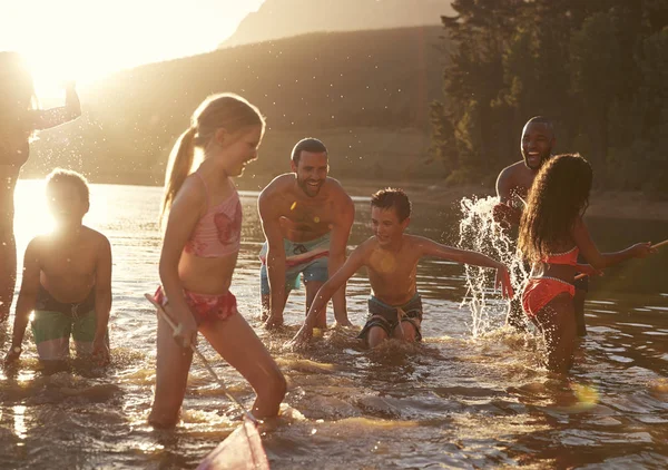 家庭与朋友享受晚上游泳在乡下湖 — 图库照片