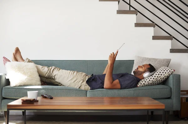 Muž Leží Pohovce Doma Nosit Sluchátka Sledování Filmu Digitální Tablet — Stock fotografie