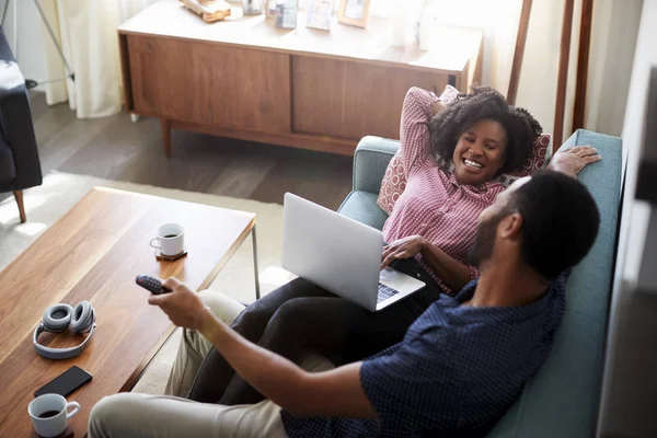 Pareja Sentada Sofá Casa Usando Ordenador Portátil Viendo Televisión — Foto de Stock