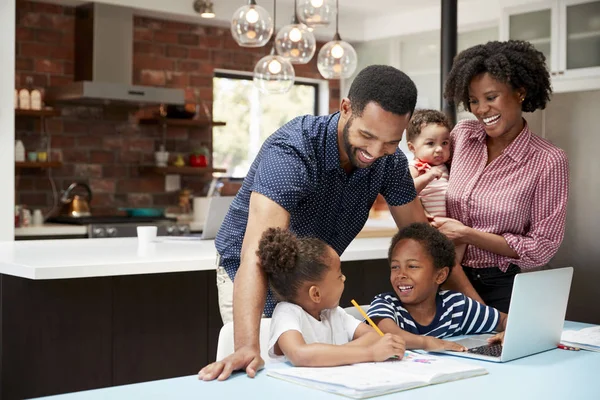 Padre Ayudando Los Niños Con Tarea Mientras Madre Sostiene Bebé — Foto de Stock