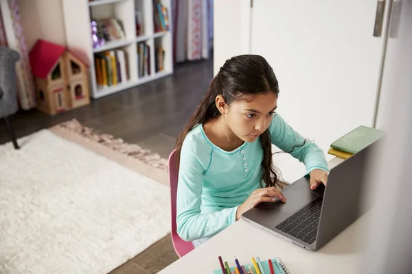 坐在办公桌在卧室的年轻女孩使用笔记本电脑 — 图库照片