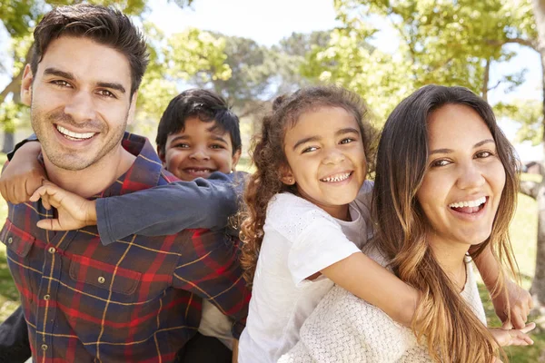Young Parents Piggybacking Two Kids Outdoors — Stock Photo, Image