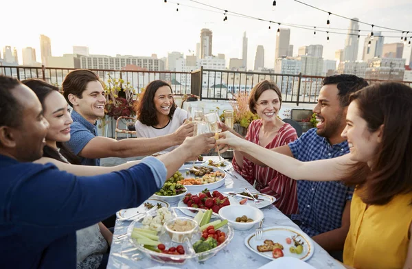 Vrienden Verzameld Dakterras Voor Maaltijd Met Skyline Van Stad Achtergrond — Stockfoto